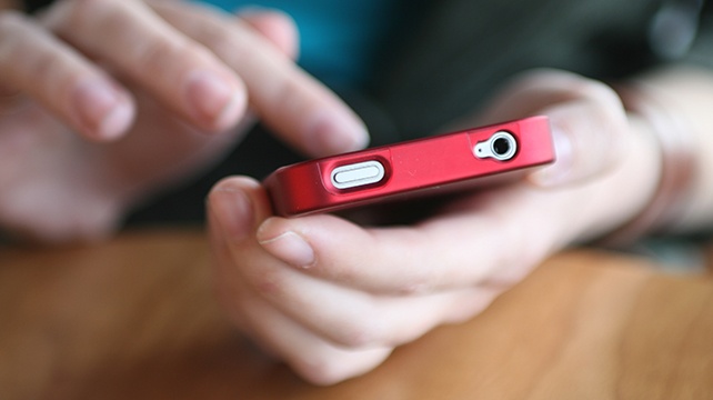 Young Woman's Hands Holding Red Smart Phone ** Note: Shallow depth of field